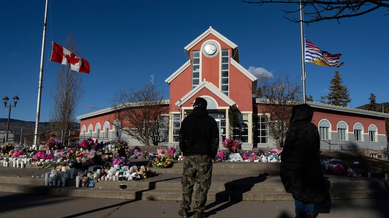 FILE - People pay their respects at a memorial on the steps of the Town Hall, following a...